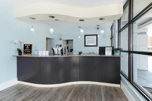 a bar in the middle of a room with windows at John Yancey Oceanfront Inn in Kill Devil Hills