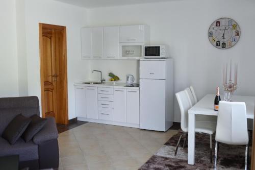 a kitchen with white cabinets and a table and a couch at Apartman Livno in Livno