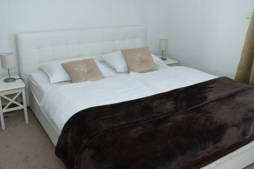 ein Schlafzimmer mit einem großen weißen Bett mit zwei Tischen in der Unterkunft Apartman Livno in Livno