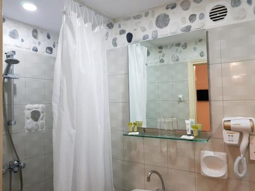 a bathroom with a shower with a white shower curtain at Anema By The Sea Guesthouse in Karlovasi