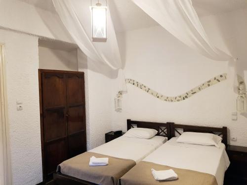 two beds in a white room with a window at Anema By The Sea Guesthouse in Karlovasi
