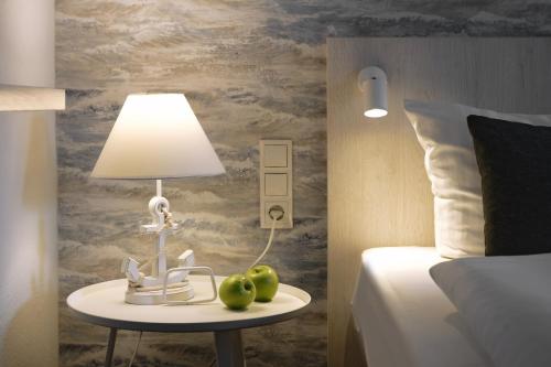 a bedroom with a table with a lamp and two apples at Trend Hotel in Oldenburg