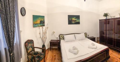 een slaapkamer met een bed en een stoel en een klok bij Rezis sweet home in Tbilisi City
