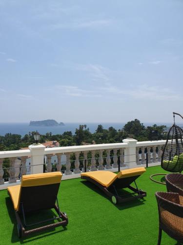 a balcony with chairs and a swing on the grass at GoldOne Hotel & Suites in Seogwipo