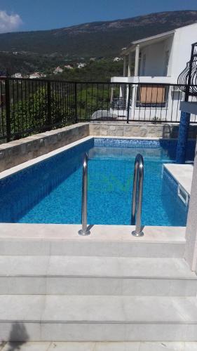 a swimming pool with stairs next to a house at Apartments Bellavista in Luštica