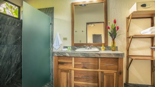 a bathroom with a sink and a mirror at La Finca Lodge in Fortuna