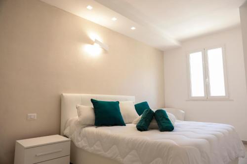 a white bedroom with a bed with green pillows at R & D in Alghero