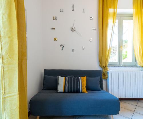 a clock on the wall above a blue couch at Villa dei Venti - Comfort Holiday in Bergamo