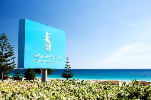 a sign for a beach with the ocean in the background at Seashells Scarborough in Perth