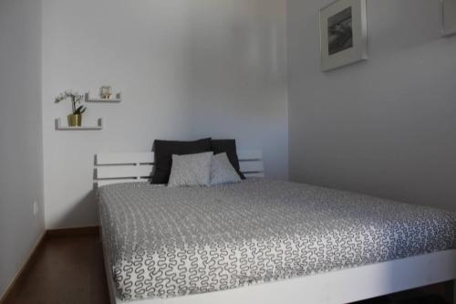 a bed in a bedroom with a white wall at Casa da Maçã in Sesimbra