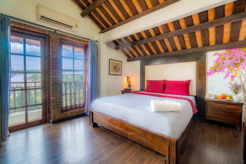 1 dormitorio con 1 cama con almohadas y ventanas de color rojo en Calm House Hotel Hoi An 1 en Hoi An