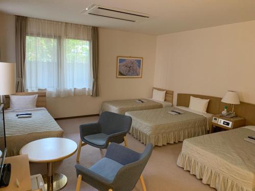a hotel room with two beds and a table and chairs at Seto Park Hotel in Seto