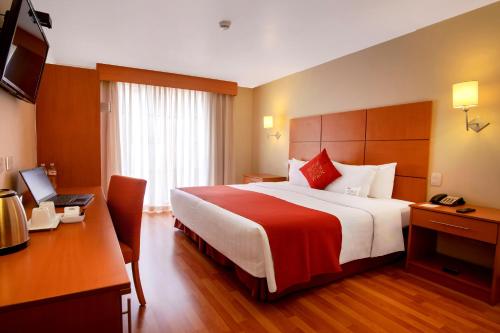 a hotel room with a large bed and a desk at Xima Exclusive Cusco in Cusco