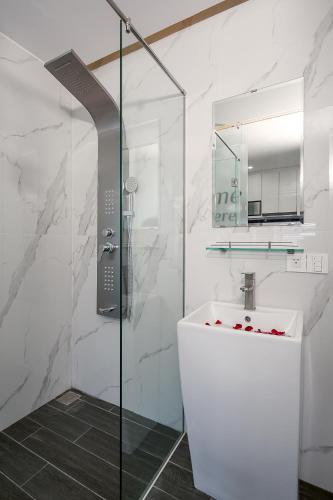a white bathroom with a shower and a sink at My Suites Danang Beach in Danang