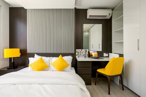 a bedroom with a bed and a desk with a yellow chair at My Suites Danang Beach in Danang