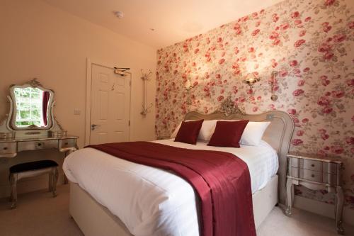 a bedroom with a bed with floral wallpaper at The Wychwood Inn in Shipton under Wychwood
