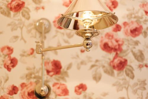 a lamp on a wall with flowers on it at The Wychwood Inn in Shipton under Wychwood