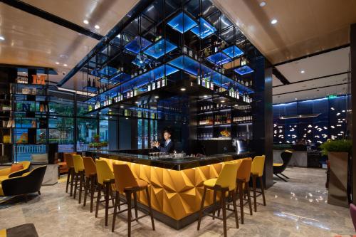 a bar in a restaurant with yellow chairs at Hampton by Hilton Yixing Renmin Middle Road Branch in Yixing