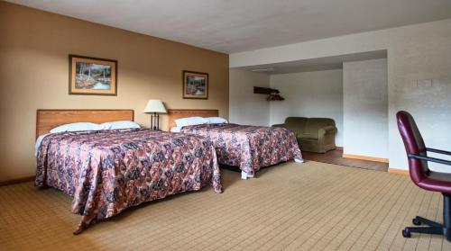 a hotel room with two beds and a chair at Campus Inn in Lafayette