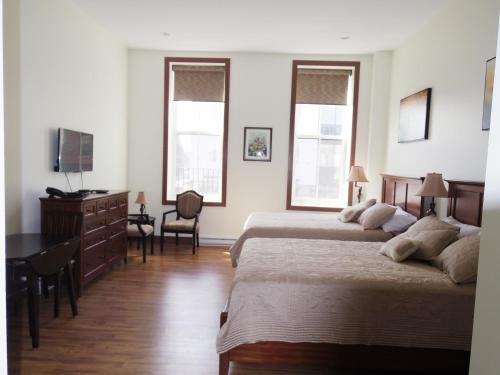a bedroom with two beds and a desk and two windows at Water Suites in Charlottetown