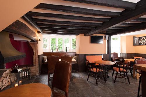 a restaurant with tables and chairs and a window at The Wychwood Inn in Shipton under Wychwood