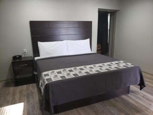 a bed with a black headboard in a room at Budget Inn & Suites Baton Rouge in Baton Rouge
