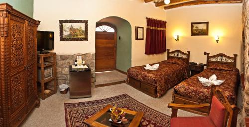 a hotel room with two beds and a tv at Hotel Marqueses in Cusco