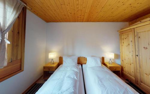 2 lits dans une chambre avec 2 lampes sur des tables dans l'établissement Maurus A3, à Saint-Moritz