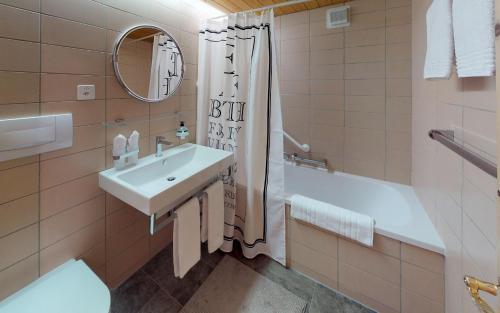 uma casa de banho com um lavatório, uma banheira e um espelho. em Maurus A3 em St. Moritz