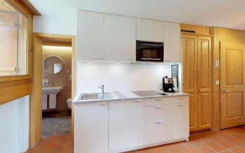 eine weiße Küche mit einer Spüle und einer Mikrowelle in der Unterkunft Maurus A4 in St. Moritz