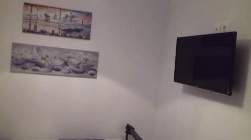 een flatscreen-tv hangend aan een muur met twee foto's bij Seaside studio for 3 people - Alykes beach in Dhimínion