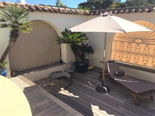 an umbrella and a chair on a wooden deck at Appartements Les Pesquiers 2 Hyères Plage in Hyères