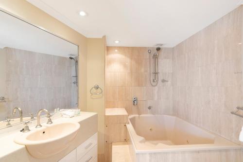 a white bathroom with a tub and a sink at 19th Avenue on the Beach in Gold Coast