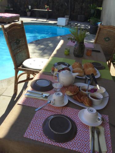a table with a plate of food on it next to a pool at Chez nous in Pereybere