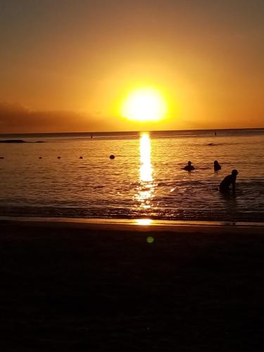 a group of people in the ocean at sunset at Chez nous in Pereybere