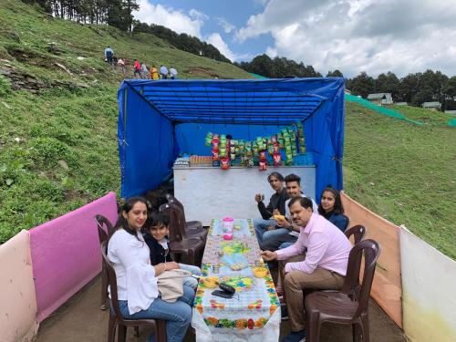 a group of people sitting at a table with a cake at DreamLand Home stay (JALORI PASS) in Shoja