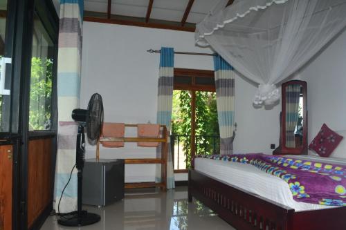 a bedroom with a bed and a fan and a window at Cloudy Hill Cottage in Ella
