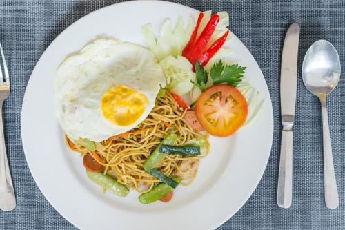 Een bord met eten, bestaande uit een ei, noedels en groenten. bij Villa Bali Blue in Jimbaran