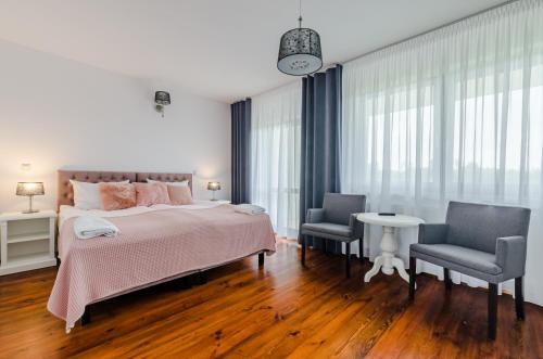 a bedroom with a large bed and two chairs at Dom Wczasowy Stenka in Gowidlino