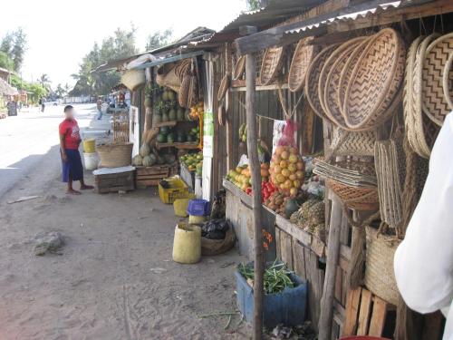 a woman standing in front of a market with fruits and vegetables at Fortamu Twiga-House in Watamu
