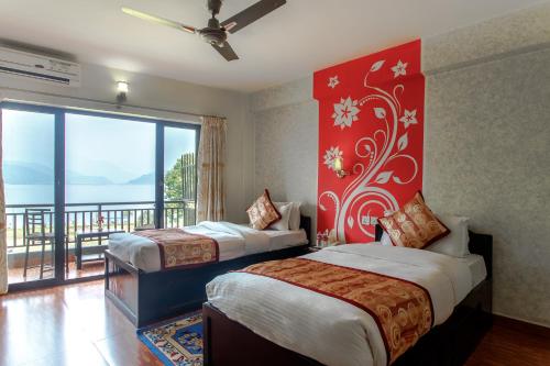 a hotel room with two beds and a balcony at Hotel Peace Plaza in Pokhara
