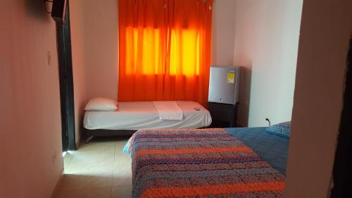 a room with two beds and a window with an orange curtain at cabañas Juakianna in Tolú