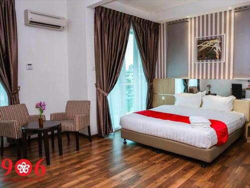 マラッカにある906 Premier Hotelのベッド、テーブル、椅子が備わるホテルルームです。
