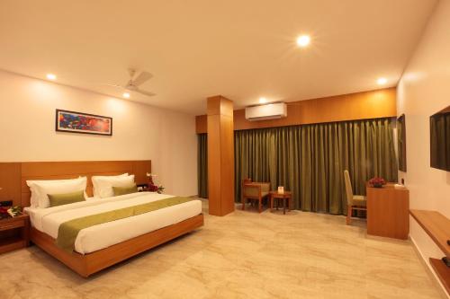 a hotel room with a bed and a table and chairs at Hotel Park Residency Thrissur in Trichūr