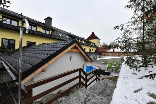 a house with a black roof with snow on the stairs at Wellness Hotel Fridrich in Horní Těrlicko