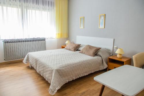 a bedroom with a bed and a table and a window at Apartman Japlenški in Delnice
