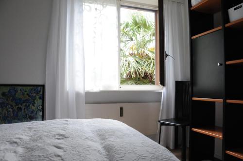 - une chambre avec un lit blanc et une fenêtre dans l'établissement Acquachiara, à Ponte Tresa