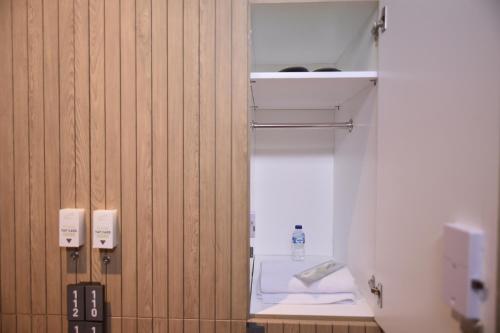 Habitación con paredes de madera y baño con aseo. en Whiz Capsule Hotel Thamrin Jakarta, en Yakarta