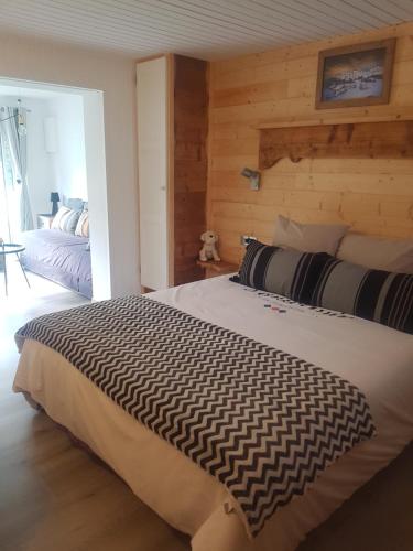 1 dormitorio con 1 cama grande y pared de madera en TISHA, en Saint-Jorioz