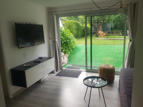 - un salon avec une télévision et une porte coulissante en verre dans l'établissement TISHA, à Saint-Jorioz